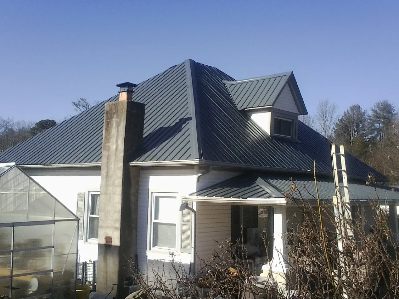 Dark blue standing seam metal roof on a white farmhouse with dormer — Slate & Tile Roof Repair by Roofing Brothers in Kirkman