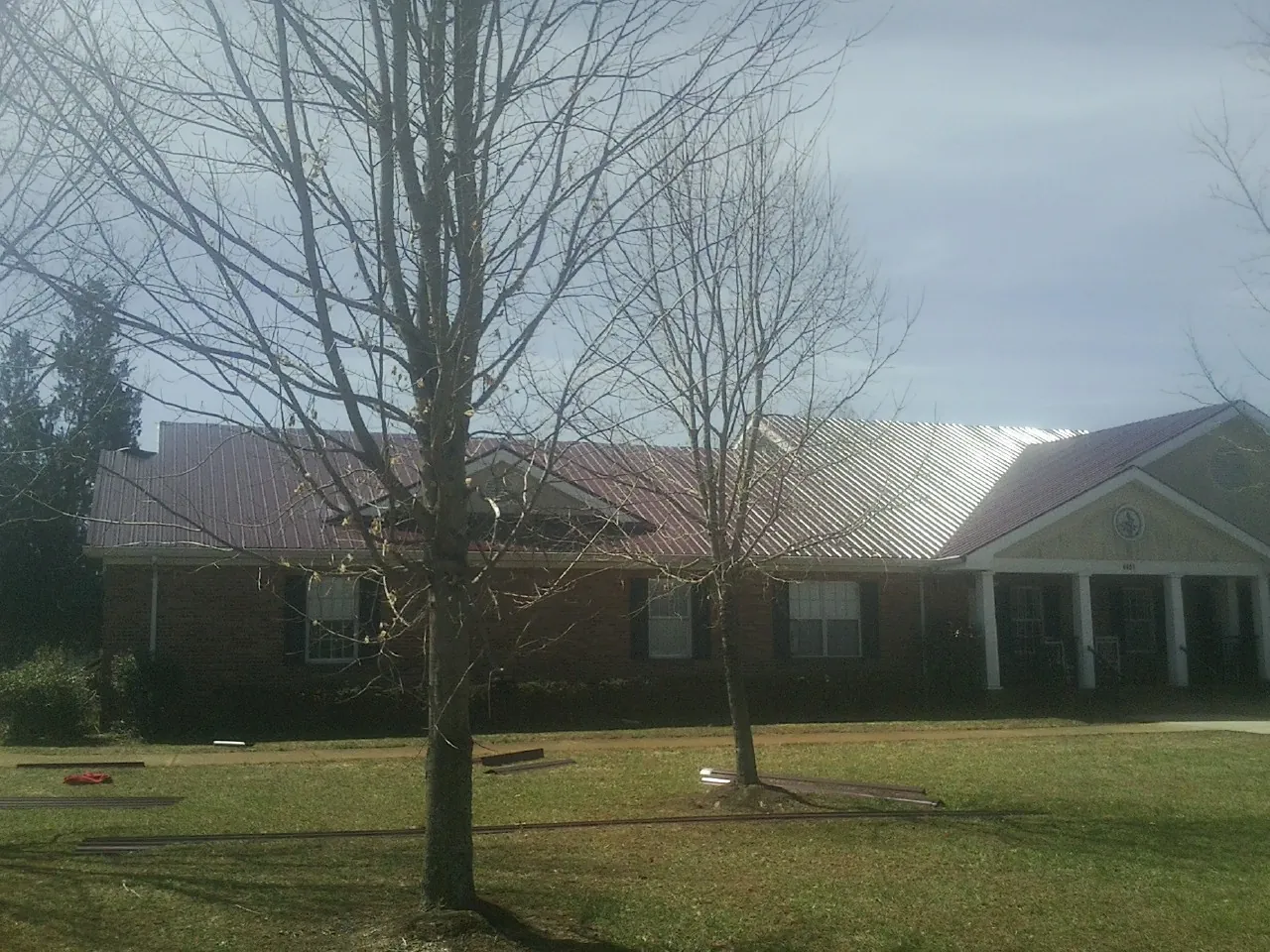 Red metal roof on a brick building seen from the front lawn in Kirkman