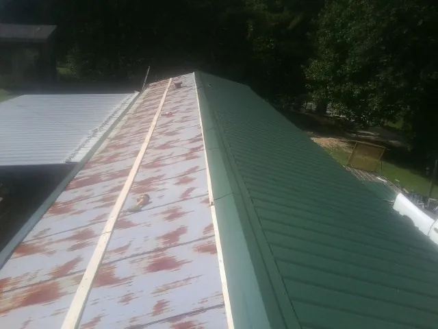 Old rusted panels beside newly installed green metal roofing — Wind Damage Roof Repair by Roofing Brothers in Kirkman