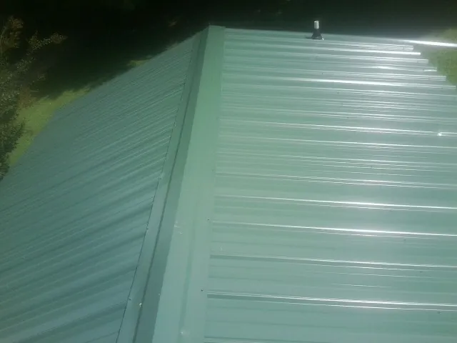 New green metal panels meeting at the ridge of a roof — Flat Roof Repair work by our crew in Kirkman