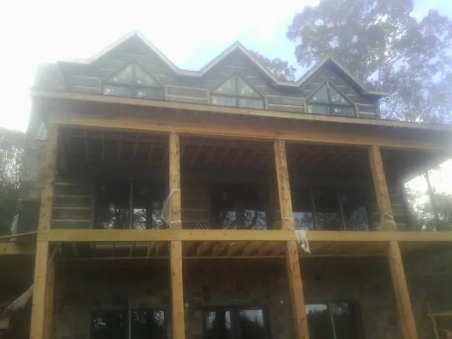 Dormers and porch framing on a large log home under construction — Roof Coating work by our crew in Kirkman
