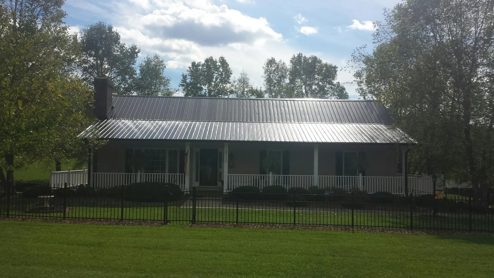 Gray metal roof on a brick ranch with a full width front porch — Gutter Guard Installation work by our crew in Kirkman