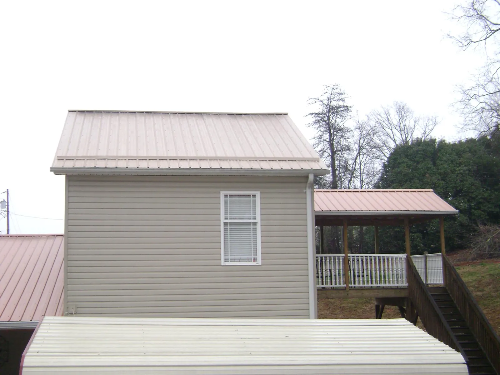 Tan metal roofs on a two story addition and attached porch, from a Roof Replacement job in Kirkman