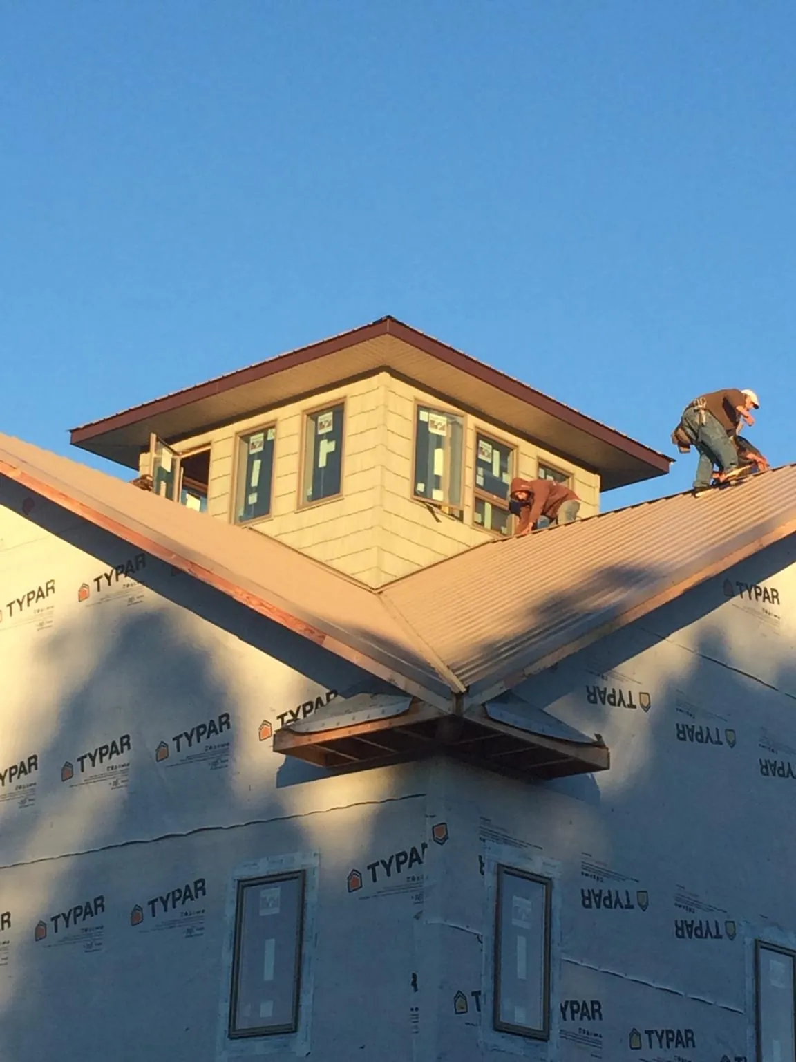 Roofers working around a rooftop cupola on a new metal roof at sunset — Roof Waterproofing in Kirkman by Roofing Brothers